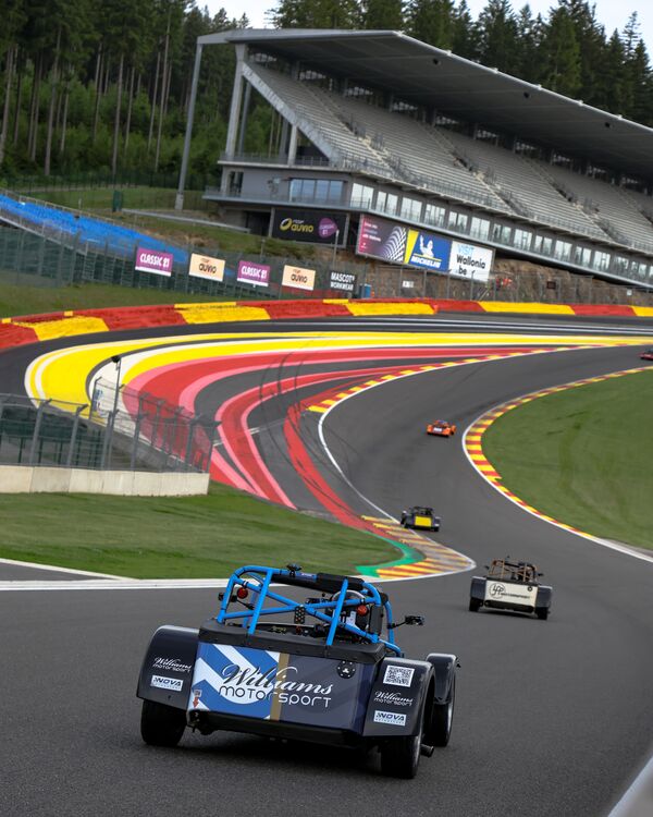 Caterham Seven 270R seen from behind, heading into Raidillon at Spa-Francorchamps beneath the main grandstand